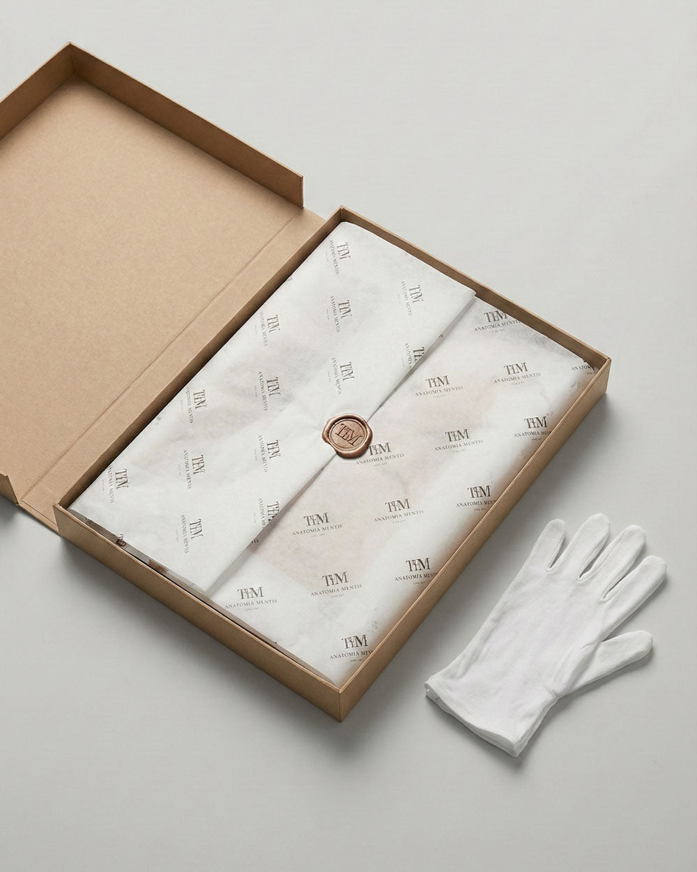 Confezione regalo premium per stampe d'arte Lorenzo Caia. Scatola rigida protettiva, opera avvolta in carta velina con sigillo in ceralacca e guanti bianchi in cotone per la manipolazione sicura dell'opera.