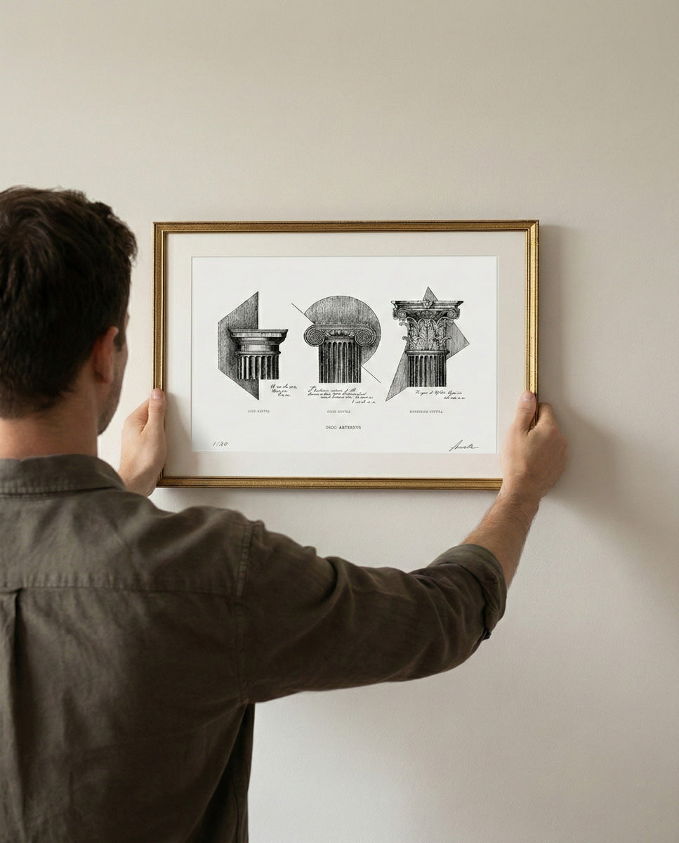Persona che regge tra le mani l'opera "Ordo Aeternus" in formato A3 con cornice dorata. Riferimento visivo per le dimensioni reali della stampa architettonica appesa a parete.
