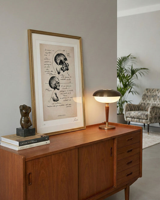 Stampa anatomica del cranio "Anatomia Mentis" incorniciata e appoggiata su credenza in legno stile mid-century modern. Arredamento d'interni per studio professionale o salotto elegante.